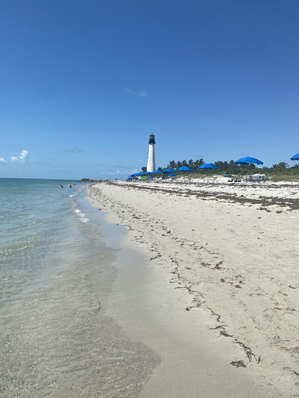 white and black lighthouse on beach during daytime