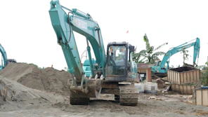green and black excavator on brown sand during daytime