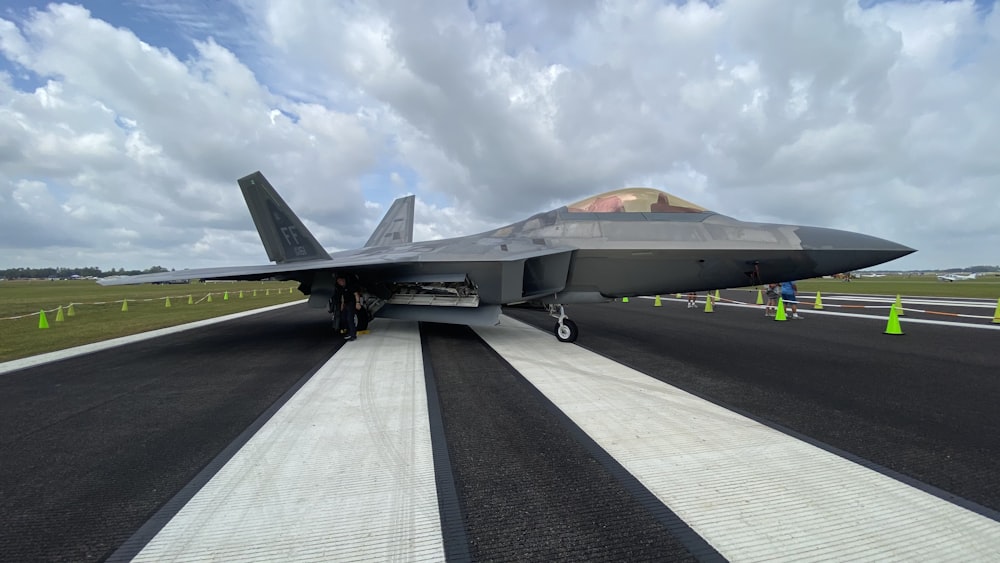 avion de chasse noir sur un trottoir en béton gris pendant la journée