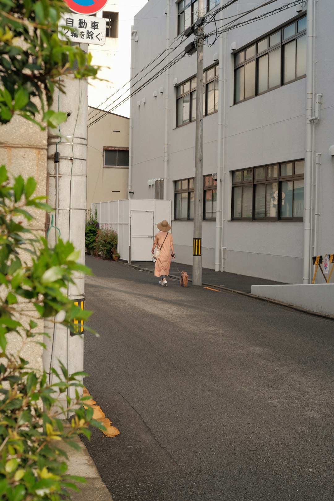 woman in white coat walking on sidewalk during daytime