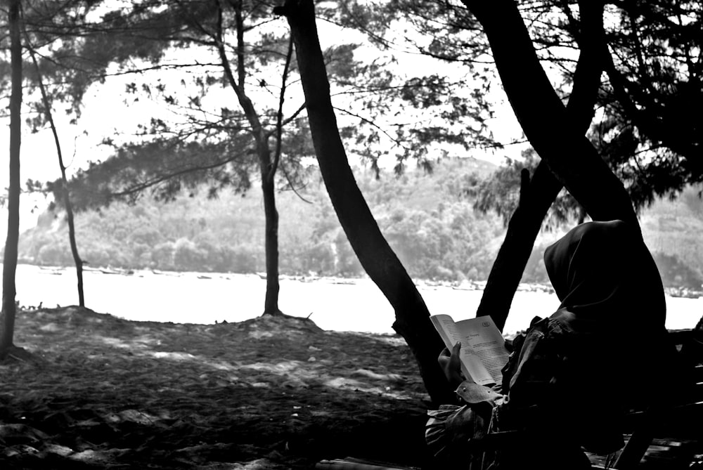 grayscale photo of woman sitting on tree branch