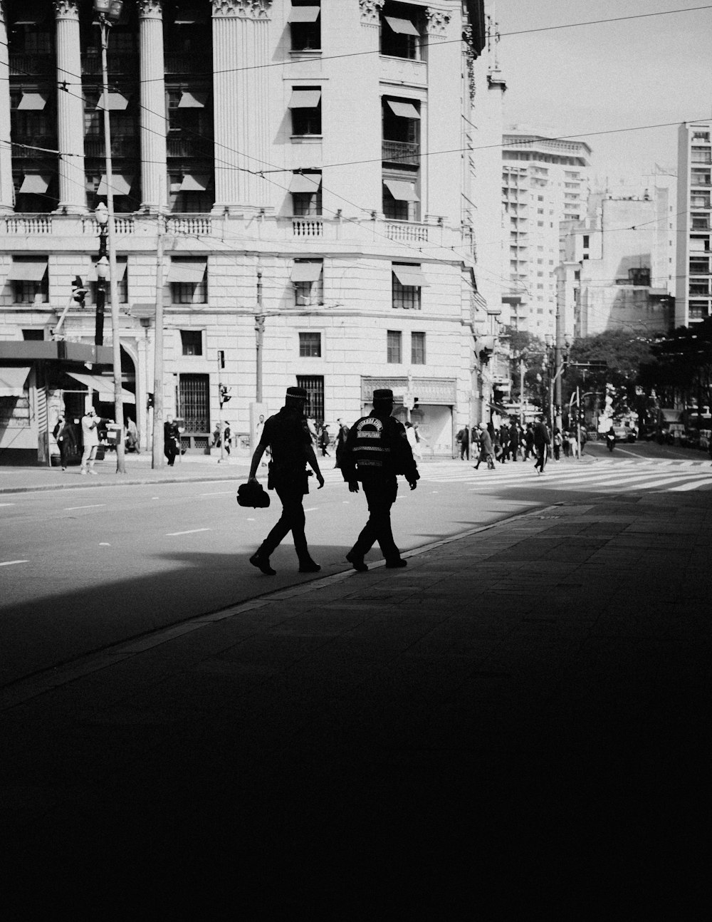 grayscale photo of man walking on sidewalk