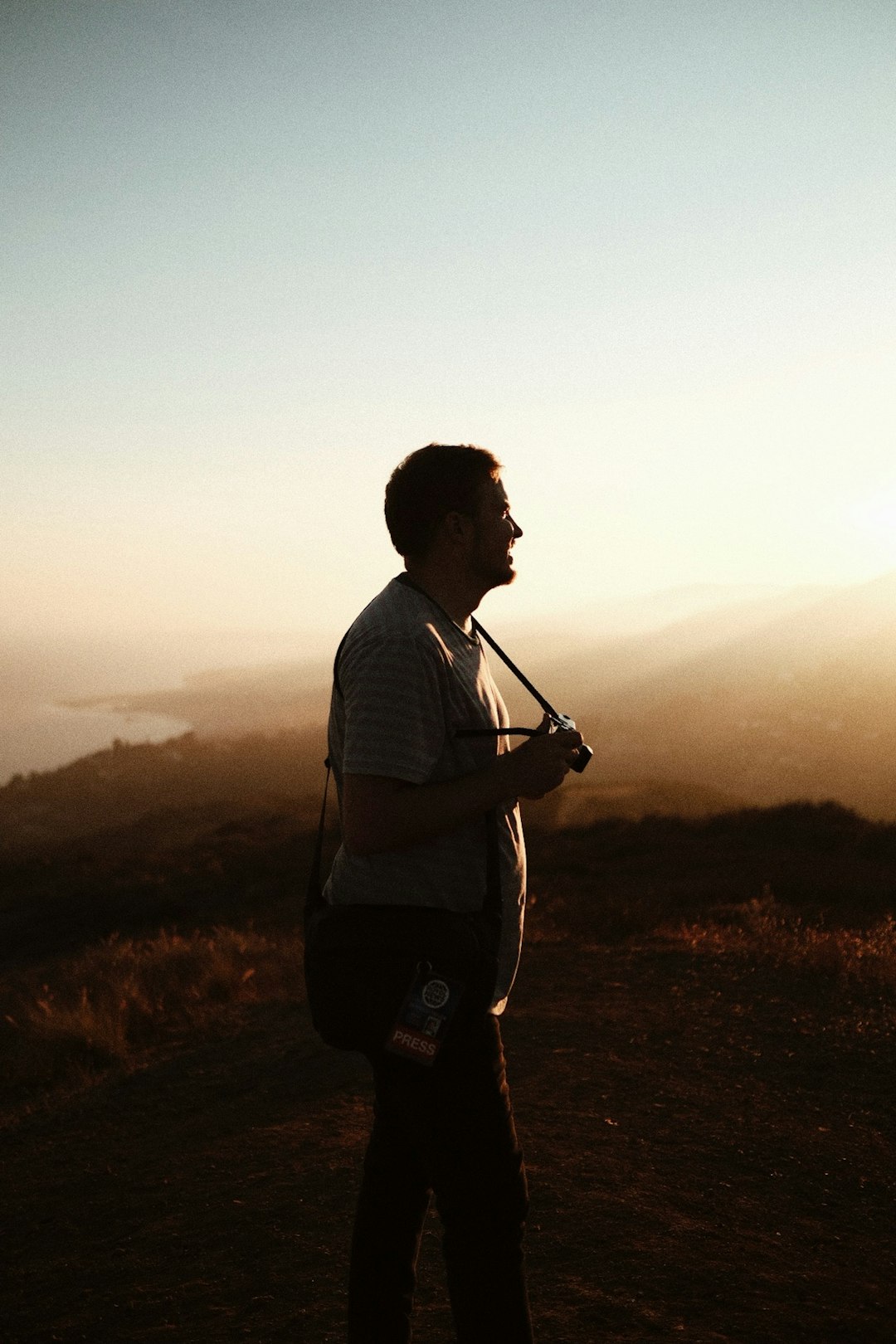 man in white and black stripe shirt standing on brown grass field during sunset