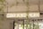 A rectangular sign with the words 'WORK HARD' is suspended from the ceiling. The background includes structural elements like pipes and beams, along with some greenery visible through windows.