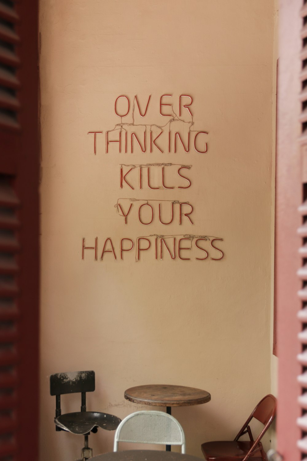 Eine Wand mit Schriftzug darauf, die besagt, dass übermäßiges Denken dein Glück tötet