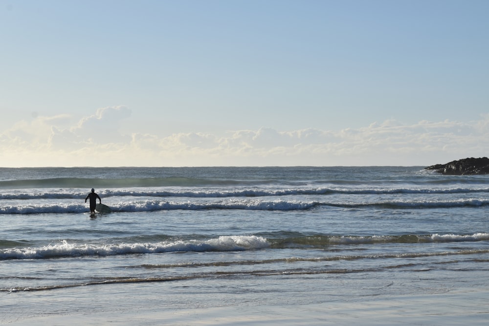 person in black wet suit standing on sea shore during daytime