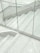 A staircase made of gray terrazzo and stainless steel lines, partially enclosed by transparent glass panels. The stair treads have several grooved lines running horizontally. The surrounding surfaces and the space appear clean and modern, with a minimalist design.