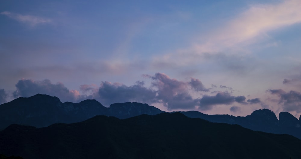 silhouette of mountain under cloudy sky during daytime