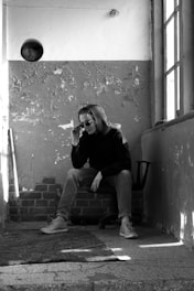 man in black jacket and pants sitting on concrete bench