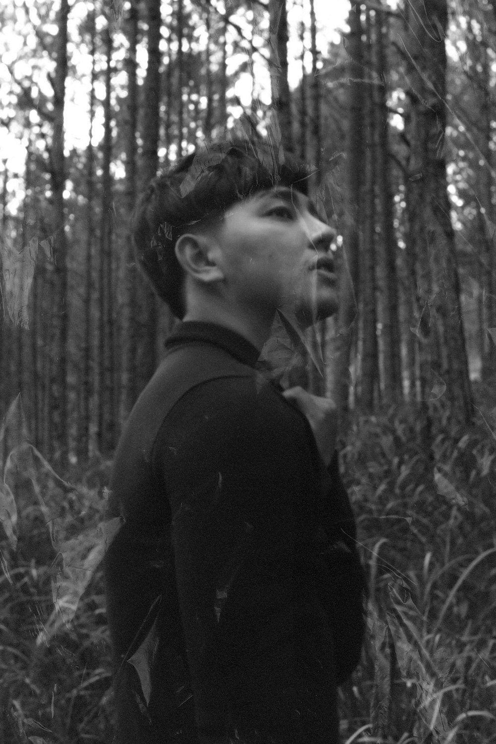 homem na camisa preta de manga comprida em pé na floresta