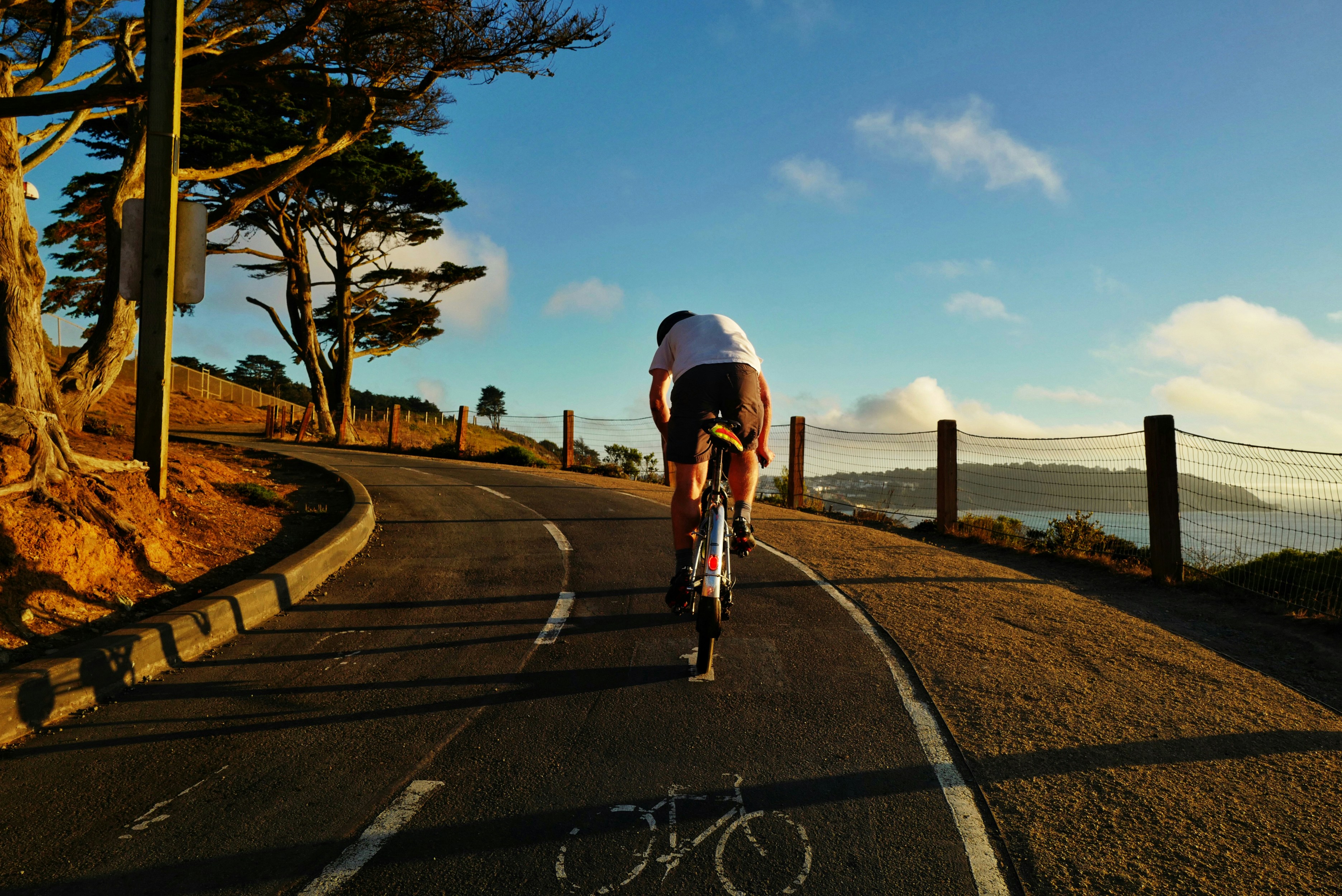 man in white shirt riding bicycle on road during daytime
