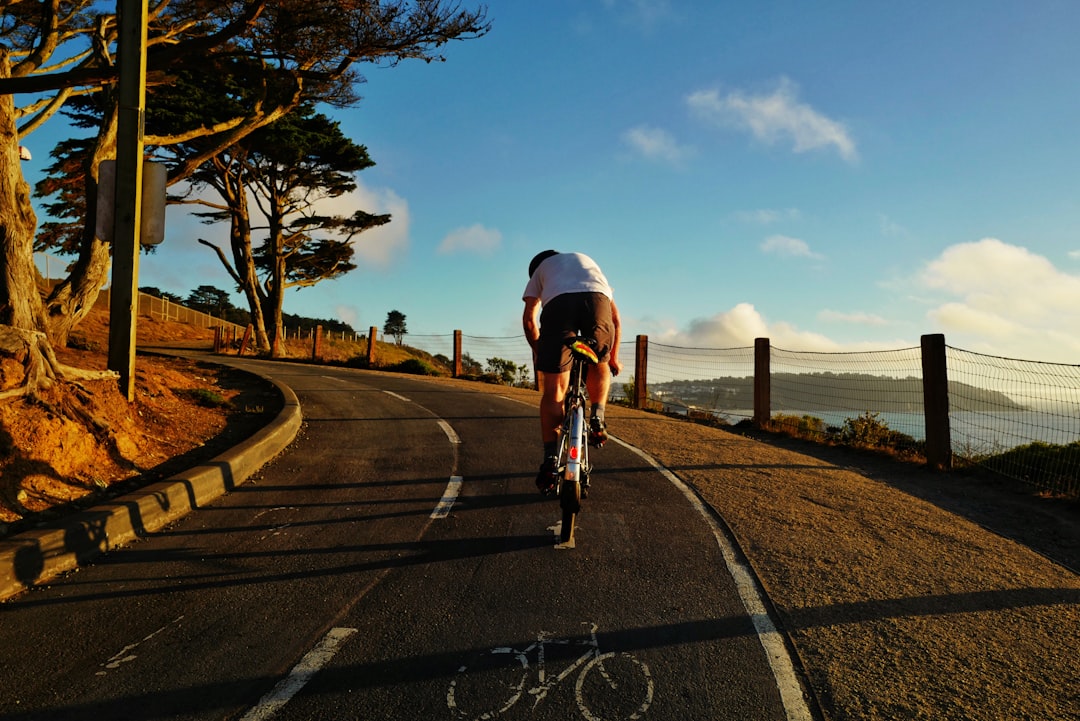 man in white shirt riding bicycle on road during daytime