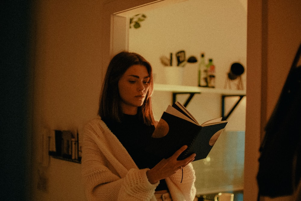 woman in white sweater holding book