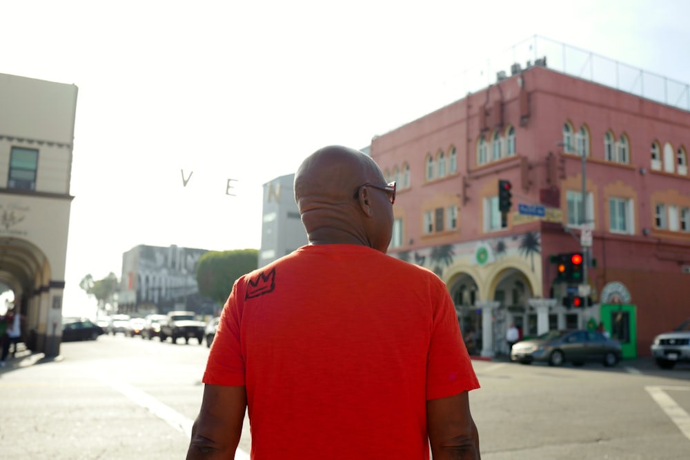 uomo in maglietta girocollo rossa in piedi sulla strada durante il giorno