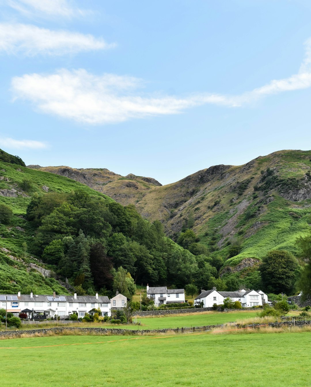 green grass field near green mountains under blue sky during daytime