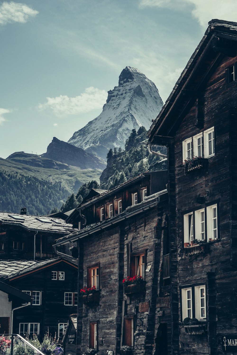 Edificio de hormigón marrón y gris cerca de la montaña cubierta de nieve durante el día