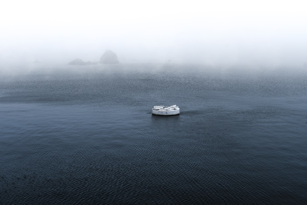 white boat on sea during foggy weather
