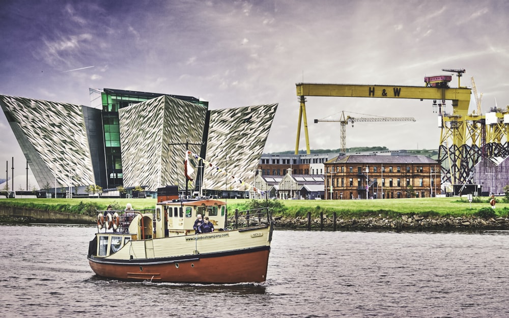 red and white boat on water near green and white building during daytime