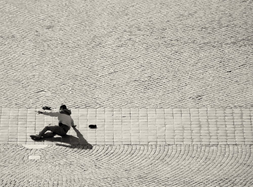 man in black shorts sitting on white concrete wall during daytime