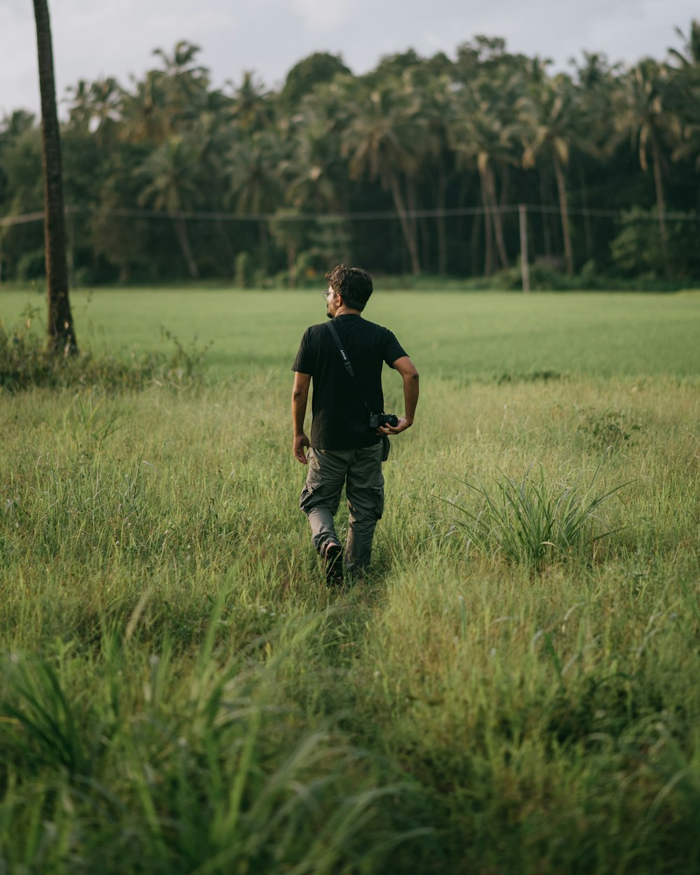 man in black t-shirt and black pants walking on green grass field during daytime