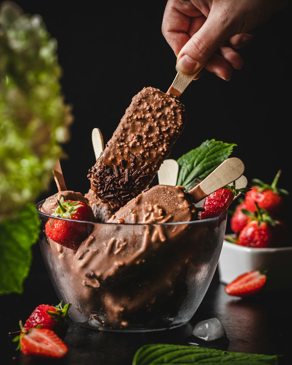 person holding ice cream with strawberry on top