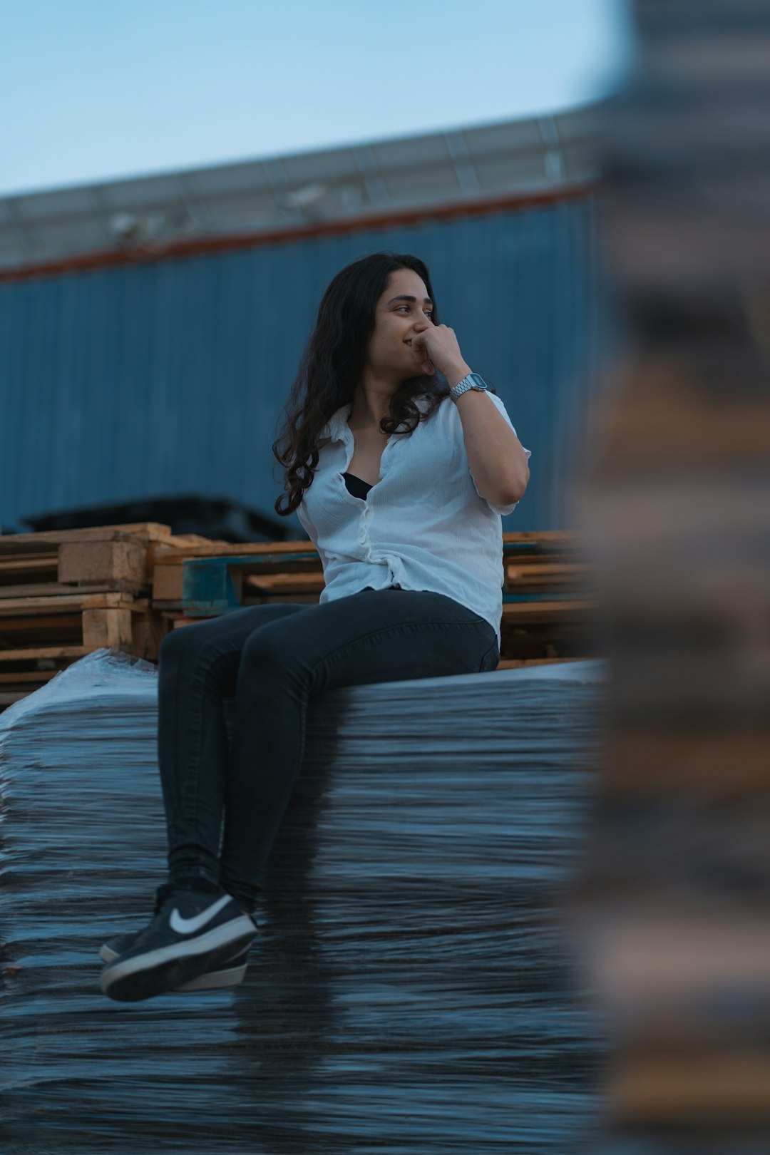 woman in white shirt and blue denim jeans sitting on wooden bench