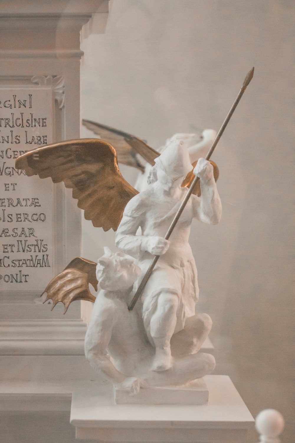 Ángel sosteniendo estatua de palo con cita