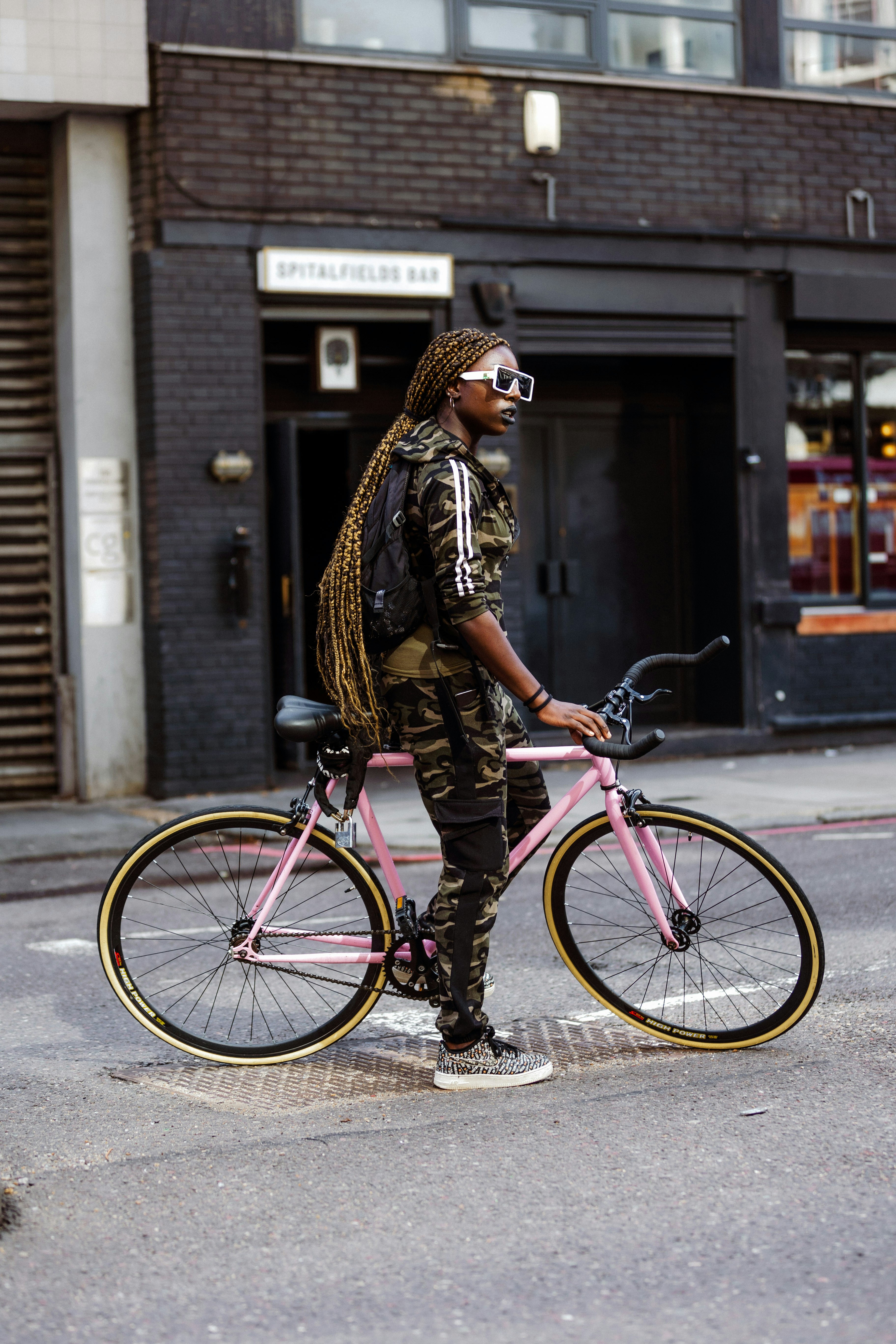 woman in brown and black leopard print jacket and black pants riding pink bicycle