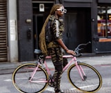 woman in brown and black leopard print jacket and black pants riding pink bicycle