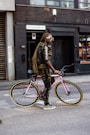woman in brown and black leopard print jacket and black pants riding pink bicycle
