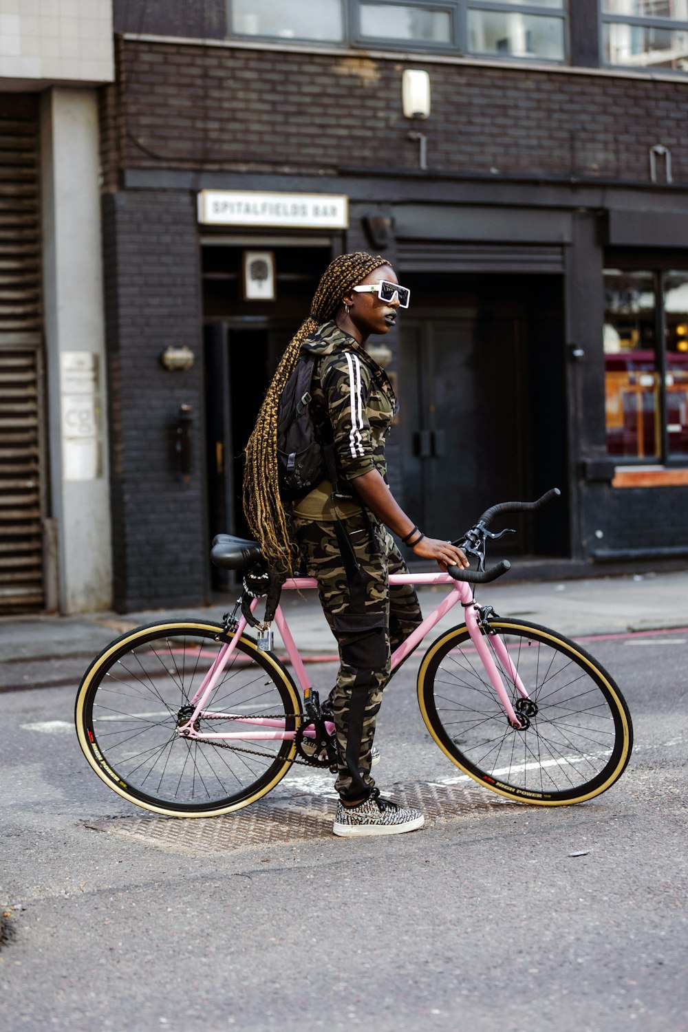 woman in brown and black leopard print jacket and black pants riding pink bicycle