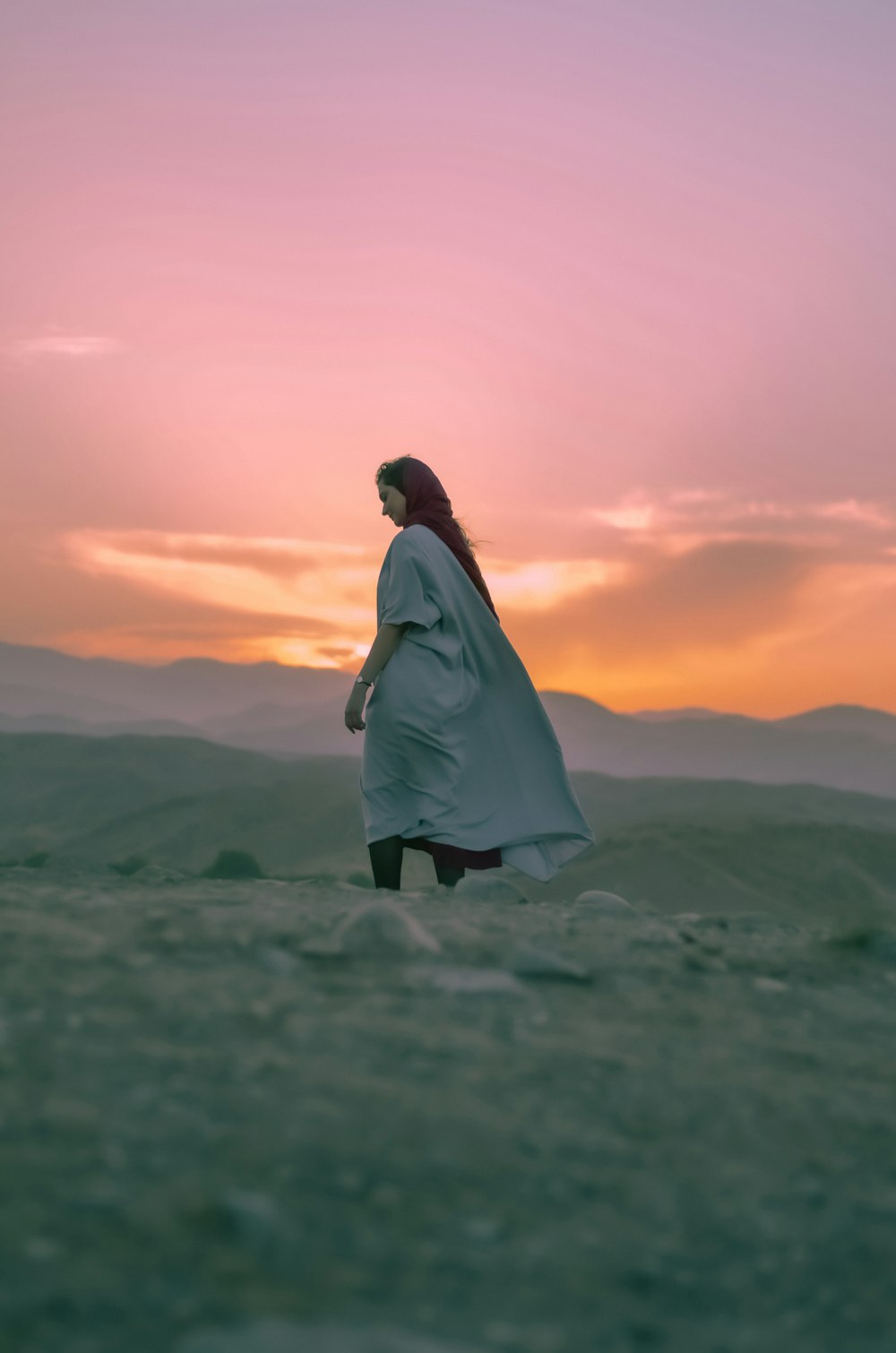 mulher no vestido branco que está no campo verde da grama durante o pôr do sol