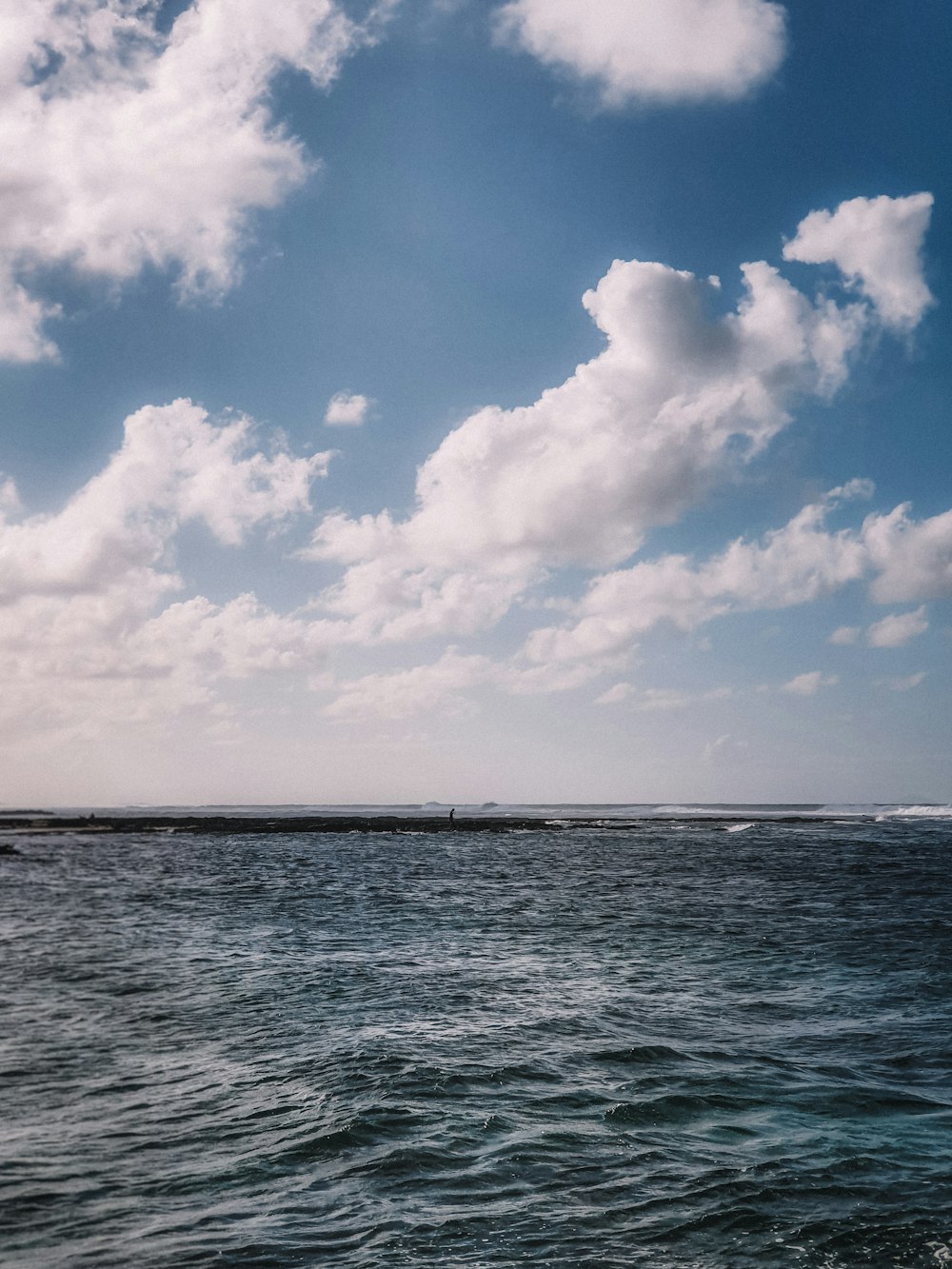 blue sea under blue sky and white clouds during daytime