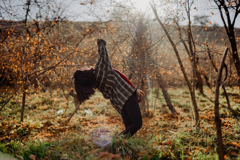 woman in black and white stripe long sleeve shirt and black pants standing on brown grass