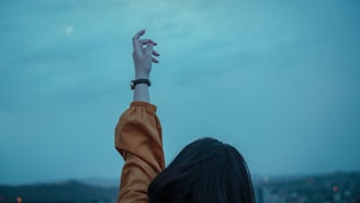 woman in brown jacket raising her left hand