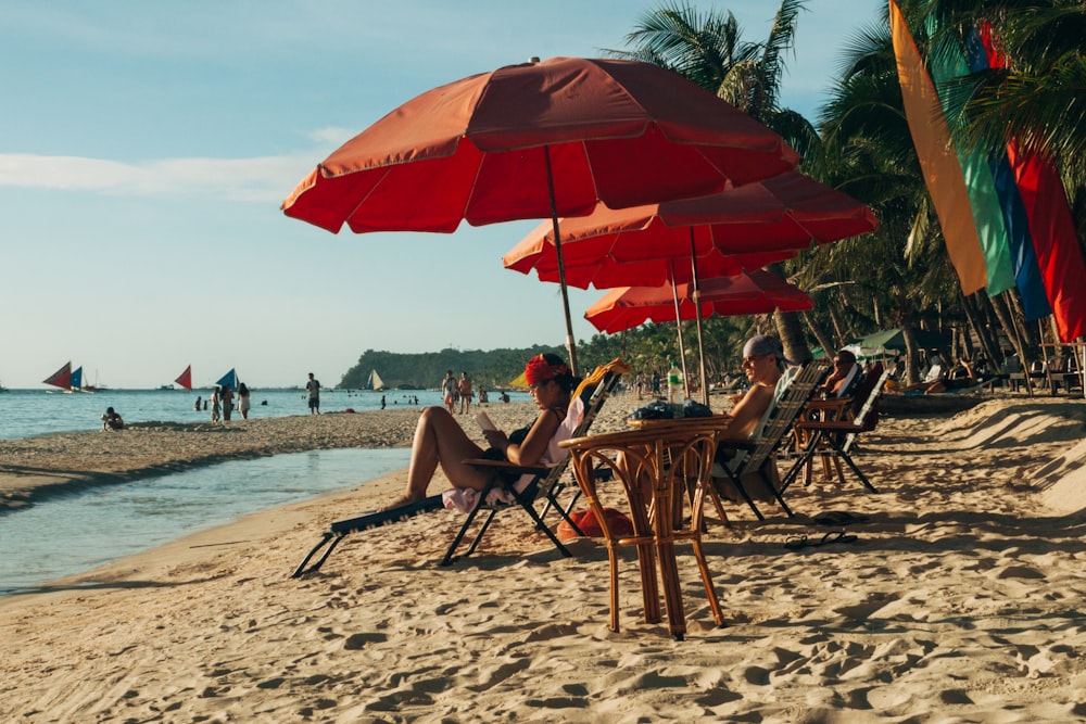 pessoas sentadas em cadeiras de madeira marrom na praia durante o dia