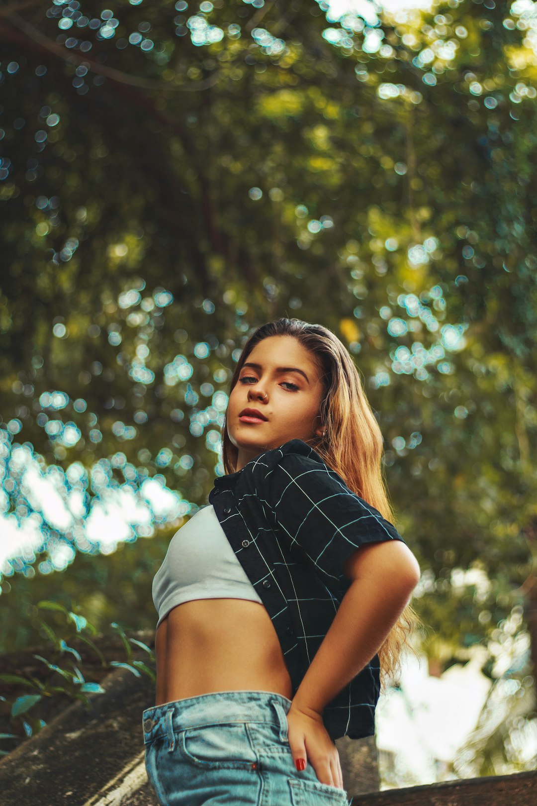 woman in black and white striped shirt standing near green trees during daytime