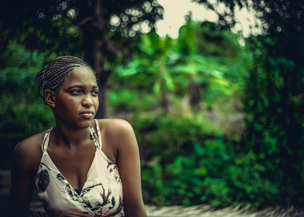 woman in white and black floral sleeveless top standing near green trees during daytime