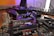 A close-up view of a complex computer motherboard with various electronic components including slots, heat sinks, and capacitors. The background features a blurred keyboard and other computer peripherals, hinting at a desktop setup.