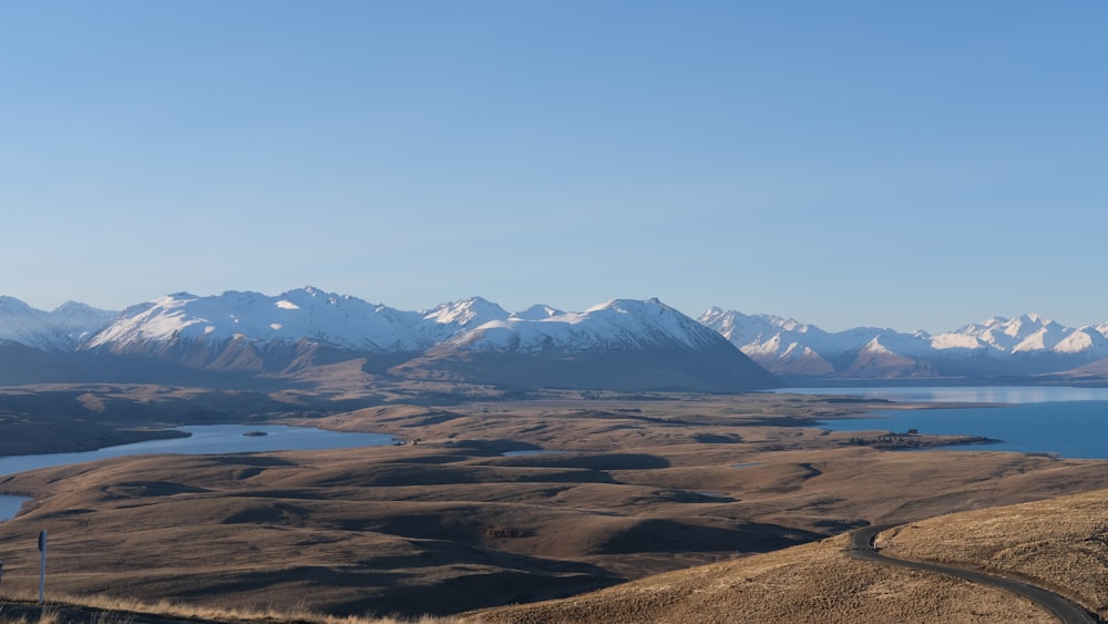 brown field near snow covered mountains during daytime