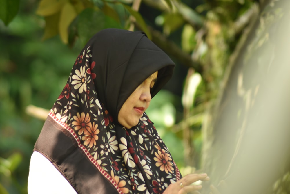 woman in black hijab standing near green trees during daytime