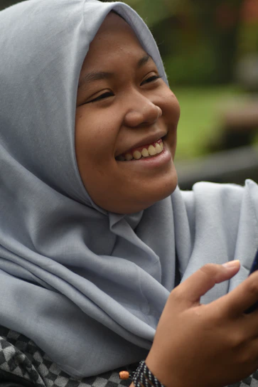 A smiling young Senegalese woman using the Kontrol app on her smartphone outdoors.