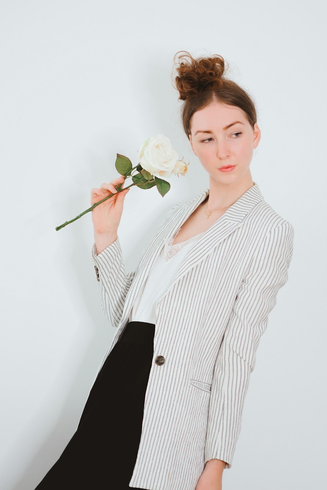 woman in white and black pinstripe dress shirt holding white rose
