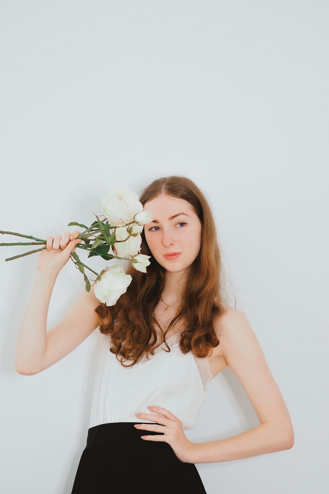 woman in white sleeveless dress holding white rose bouquet