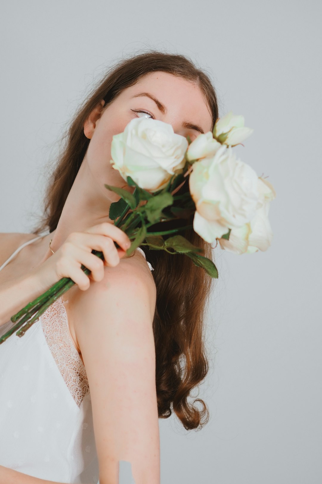 woman in white tank top holding white rose