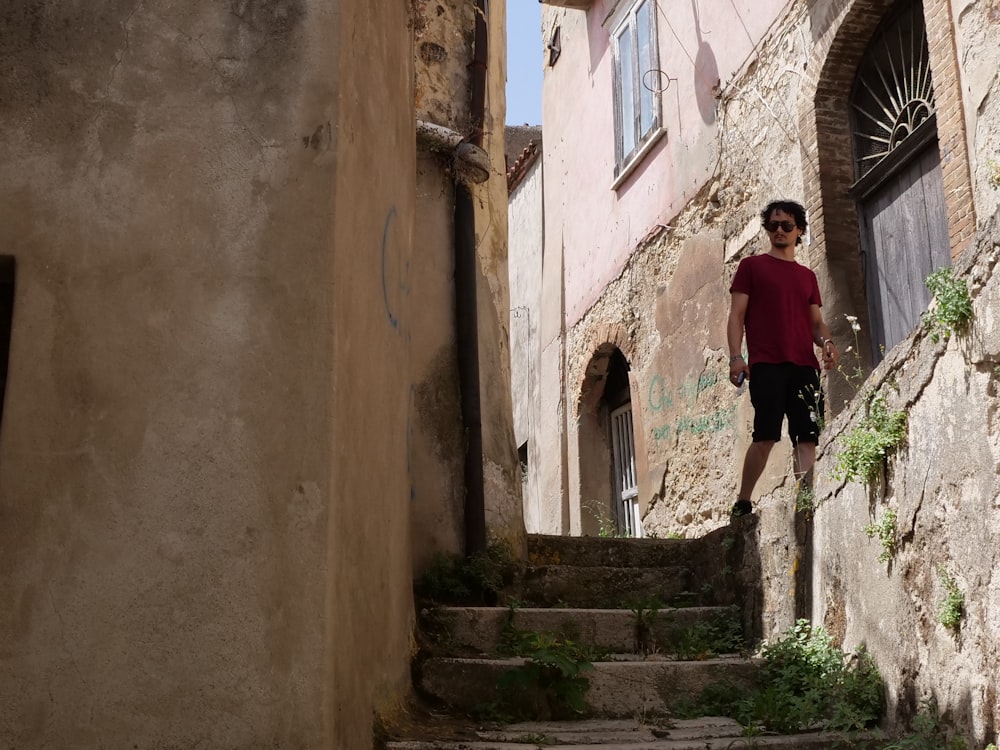 woman in pink shirt and black pants standing on stairs