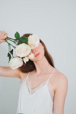 Bridal bouquet with pastel flowers held by the bride against a minimalist white background.