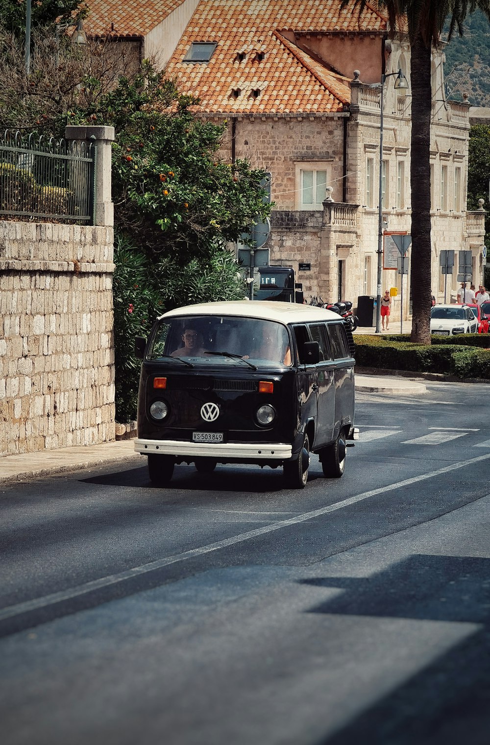 Schwarz-weißer Volkswagen T-2 parkt tagsüber neben braunem Backsteingebäude