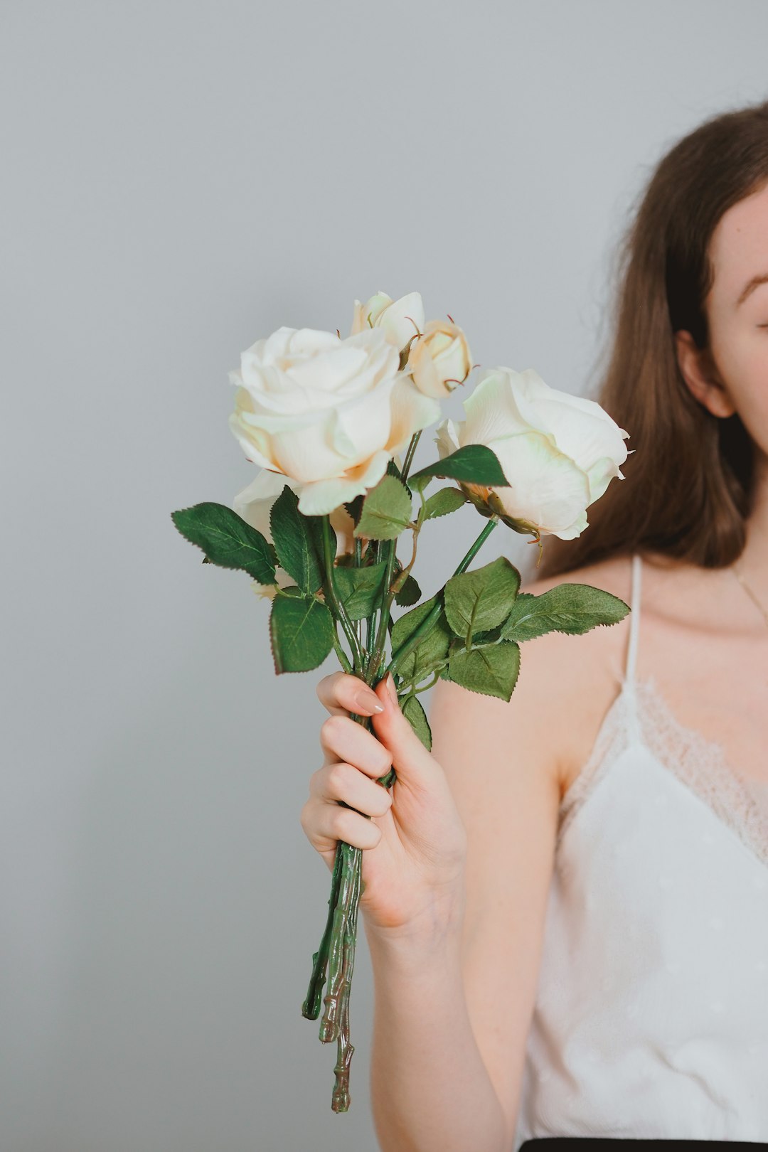 woman in white floral lace spaghetti strap top holding white rose