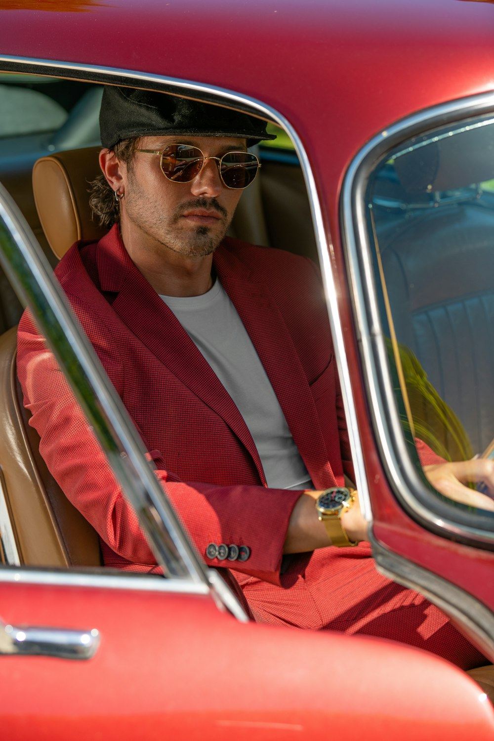 man in red suit wearing black sunglasses driving car